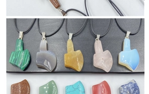 Macro shot of assorted natural stone axe pendants including rose quartz and malachite