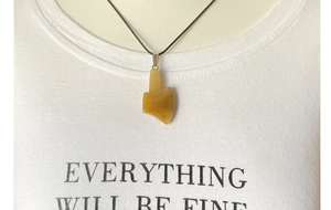 Detailed view of a yellow translucent middle finger gesture pendant on a black cord