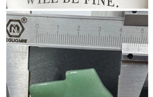 Detailed dimension measurement of green gemstone axe pendant showing 4.2cm width on caliper