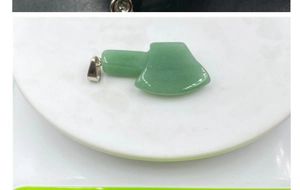 Detailed shot of axe-shaped green agate stone pendant with silver metal bail clasp