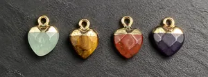 Detailed view of faceted heart-shaped pendants in dark red and purple gemstone with gold trim