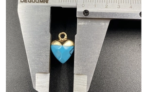 Detail view of heart-shaped turquoise pendant measured with calipers showing 13mm size