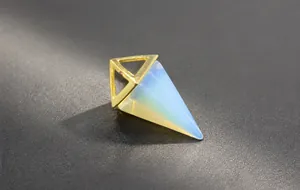Macro shot of turquoise stone pendant in pyramid shape with golden metal frame