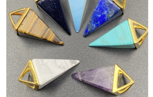 Macro shot of colorful geometric stone pendants with gold metal clips on grey background