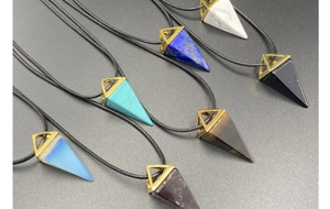 Close-up of assorted geometric cone crystal pendants with golden metal frames and cords