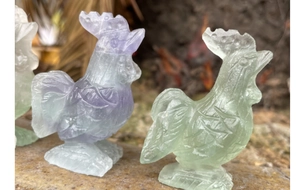 Detailed close-up showing hand-carved textures of a purple and green fluorite rooster statue