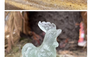 Close-up of translucent green fluorite rooster statue detailing the carved head and crest