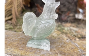 Macro shot of a hand-carved green fluorite rooster statue with translucent crystal details