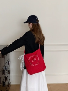 Détail du sac cabas en toile rouge avec broderie blanche et nœud en dentelle délicat