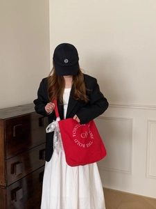 Détail du grand sac cabas en toile rouge avec broderie circulaire blanche et slogan chic