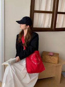 Gros plan détaillé d'un sac cabas en toile rouge avec broderie blanche et matière robuste