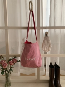 Détail du sac cabas à rayures rouges avec broderie et breloque en dentelle sur le côté