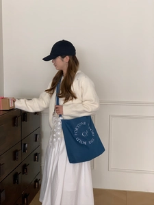 Détail d'un sac fourre-tout en toile bleue avec broderie blanche et large bandoulière