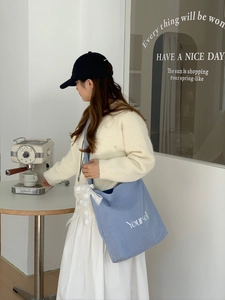 Détail du cabas en toile rayée bleue avec broderie blanche Yourself sur le côté du sac