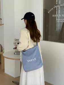 Détail du sac cabas en toile à rayures bleues avec broderie yourself dans un café