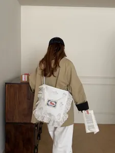 Détails d'un sac en toile blanc avec bordures en dentelle, anges et broderie cheval