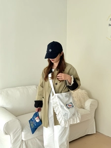 Détail du sac bandoulière en toile avec dentelle blanche et trench-coat kaki
