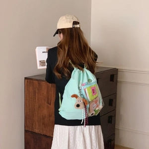 Mint green drawstring backpack with clear side pocket and plush charm on a model