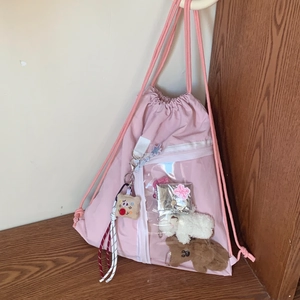 Detailed view of pink ita backpack with clear window, plush charms and drawstring closure