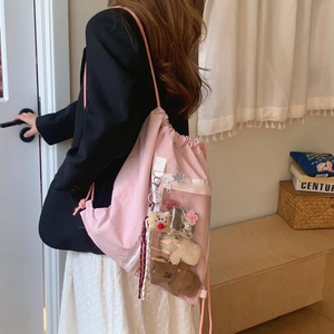 Detailed close-up of a pink drawstring backpack with a clear PVC front pocket and plush toys