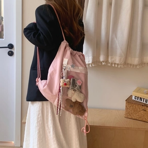 Detail of pink canvas drawstring backpack with cute embroidery patches and doll pendants