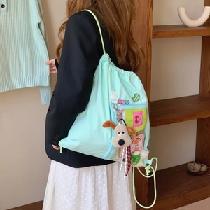 Detail of mint green drawstring backpack with transparent PVC pocket and plush charm