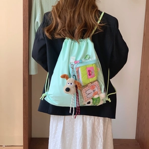 Detail view of mint green drawstring backpack with transparent pocket and plush toy