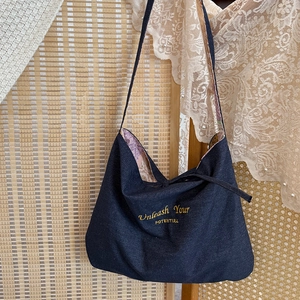 Dettaglio borsa tote in denim blu con ricamo giallo e fodera floreale in stile retrò