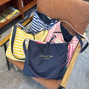 Détail des sacs bandoulière en toile rayée avec broderie de lettres en quatre coloris