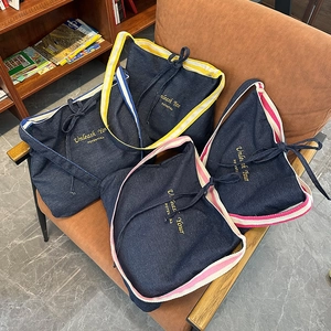 Sacs cabas en denim bleu foncé avec détails de sangles colorées et broderies sur fauteuil