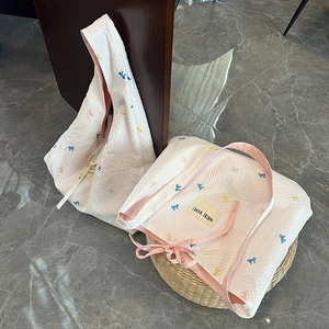 Détail du sac fourre-tout blanc matelassé avec broderies de nœuds et étiquette en tissu