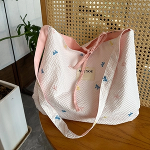 Détail du sac cabas rose gaufré avec broderies de papillons colorés et bandoulière large
