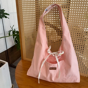 Détail du sac cabas en toile rose avec poche avant, nœud papillon et étiquette en cuir