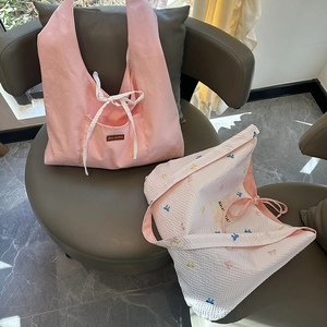 Détail du cabas en toile rose et du sac gaufré blanc avec broderie papillon et rubans doux