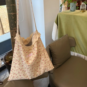 Détail du sac cabas floral avec bordure en dentelle et écusson de marque sur bois
