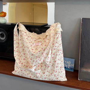 Détail du sac bandoulière en toile florale avec dentelle beige et étiquette rose