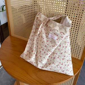 Détail du sac cabas floral avec bords en dentelle et étiquette sur une chaise vintage