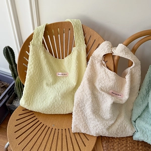 Close-up of textured bubble pleated tote bags in soft pastel yellow and cream colors