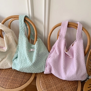 Three texture bubble tote bags in cream, green, and purple on a vintage wooden chair