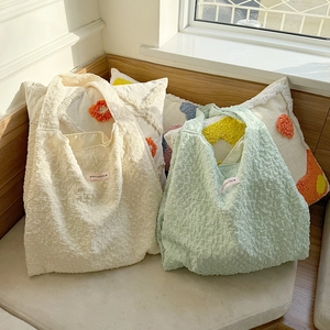 Detail of bubble textured tote bags in cream and mint green with woven design labels