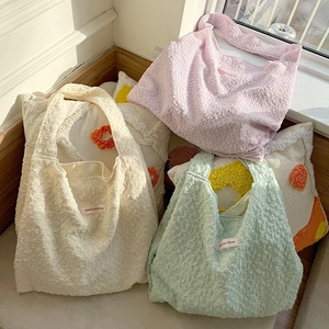 Detail of macaron pastel tote bags showing texture and 'Have a nice day' label