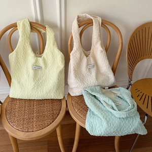 Borse shopper chic con trama a bolle in giallo, beige e verde su sedia in vimini