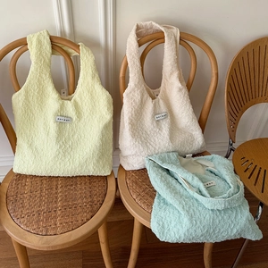 Borse tote francesi plissettate in colori pastello esposte su una sedia di legno