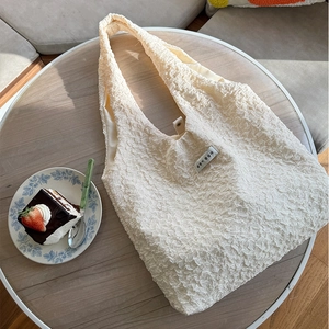 Dettaglio di una borsa tote bianca testurizzata su un tavolo in legno per un tè di stile