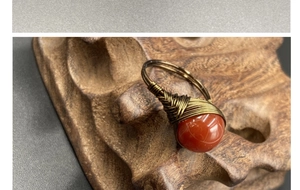 Macro view of handmade wire-wrapped ring with a polished red gemstone on wood