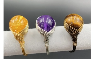 Detailed view of handmade wire wrapped rings with amethyst and tiger eye beads