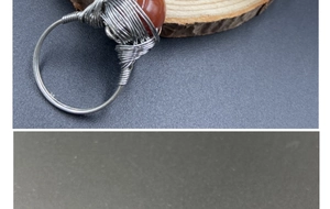 Close-up of handmade wire-wrapped ring featuring a round reddish-brown gemstone bead