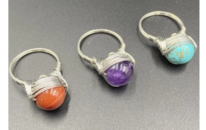 Macro shot of silver wire-wrapped rings with amethyst and turquoise gemstone beads