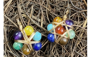 Macro detail of seven chakra natural stone pendants with gold wire wrapping on wood
