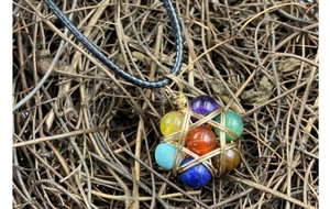 Macro shot of handcrafted seven chakra natural gemstones in golden wire-wrapped hexagram pendant